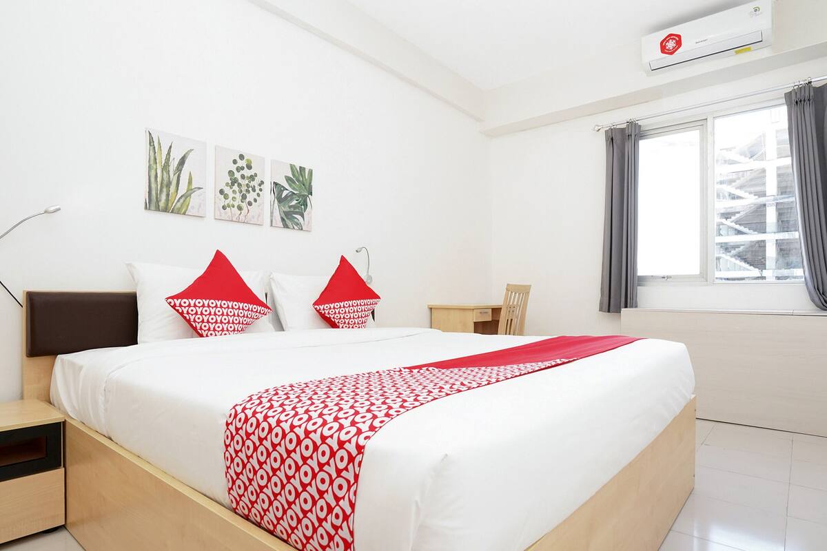 A hotel room with a bed, a desk, a chair, and a window with curtains.