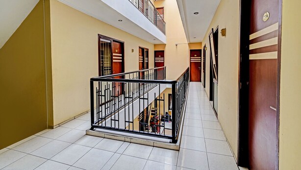 Un pasillo de hotel con suelo de baldosas, una escalera con barandilla de metal y puertas con diseño a rayas.