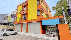 Un edificio de varios pisos con fachada de color naranja y amarillo brillante, ventanas amplias y una entrada visible en la planta baja.