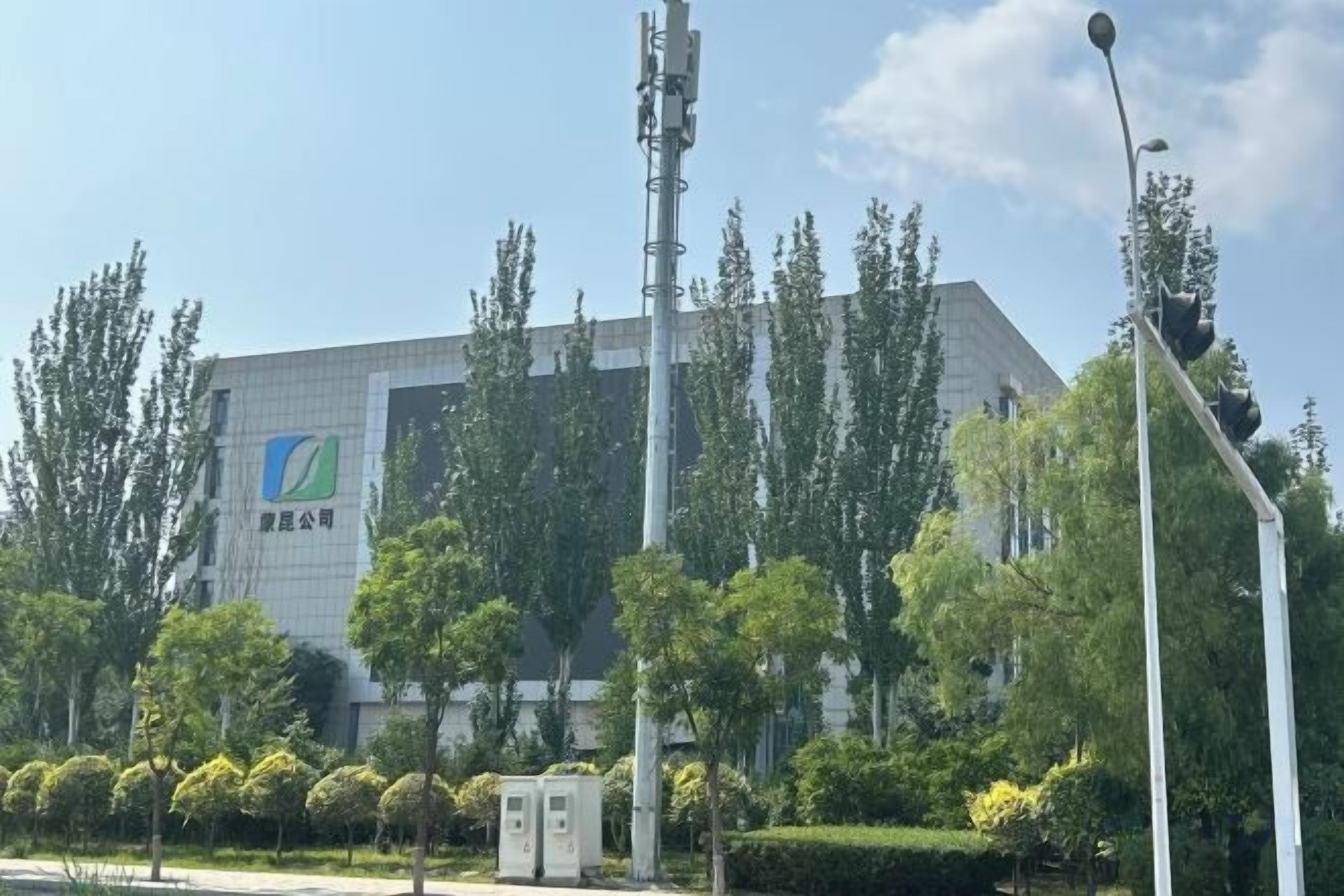 A building with a modern design, surrounded by trees and a clear sky.