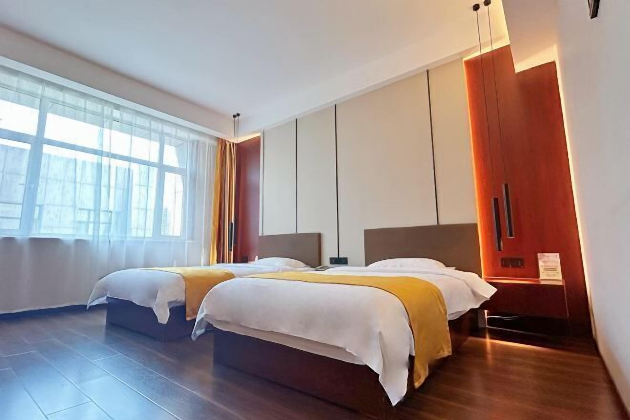 Et moderne hotelværelse med to senge, store vinduer og et træskab.