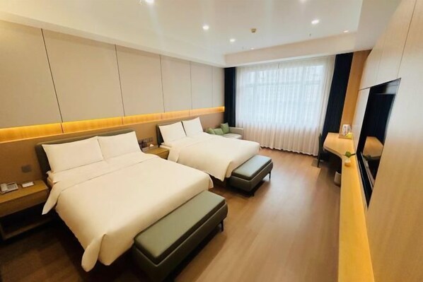 Une chambre d’hôtel avec deux lits, un téléviseur à écran plat, une grande fenêtre avec des rideaux et un plancher en bois.
