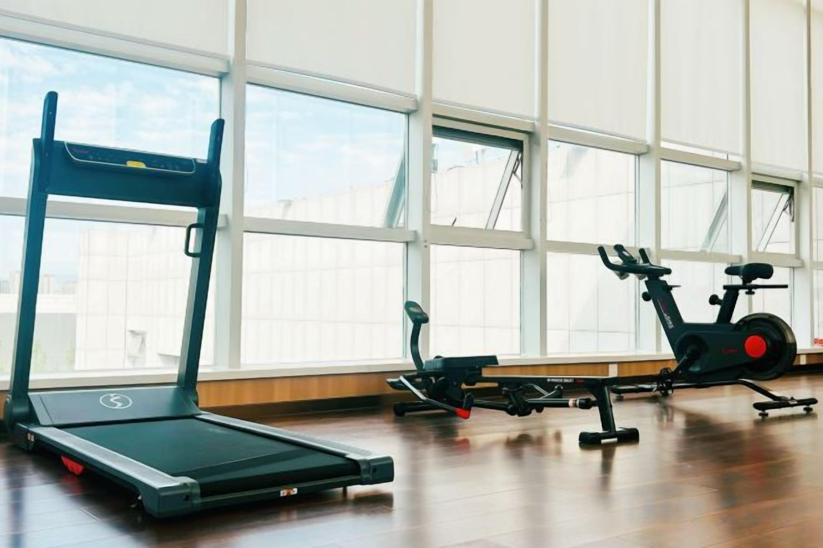 Een fitnessruimte met trainingsapparatuur, waaronder een loopband en een elliptische trainer.