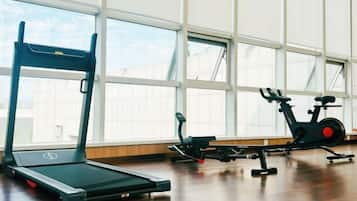 Een fitnessruimte met trainingsapparatuur, waaronder een loopband en een elliptische trainer.