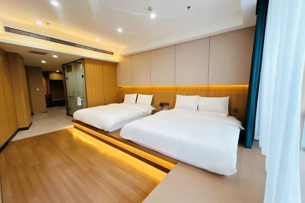 A hotel room with two beds, wooden flooring, a modern design, and a visible bathroom.