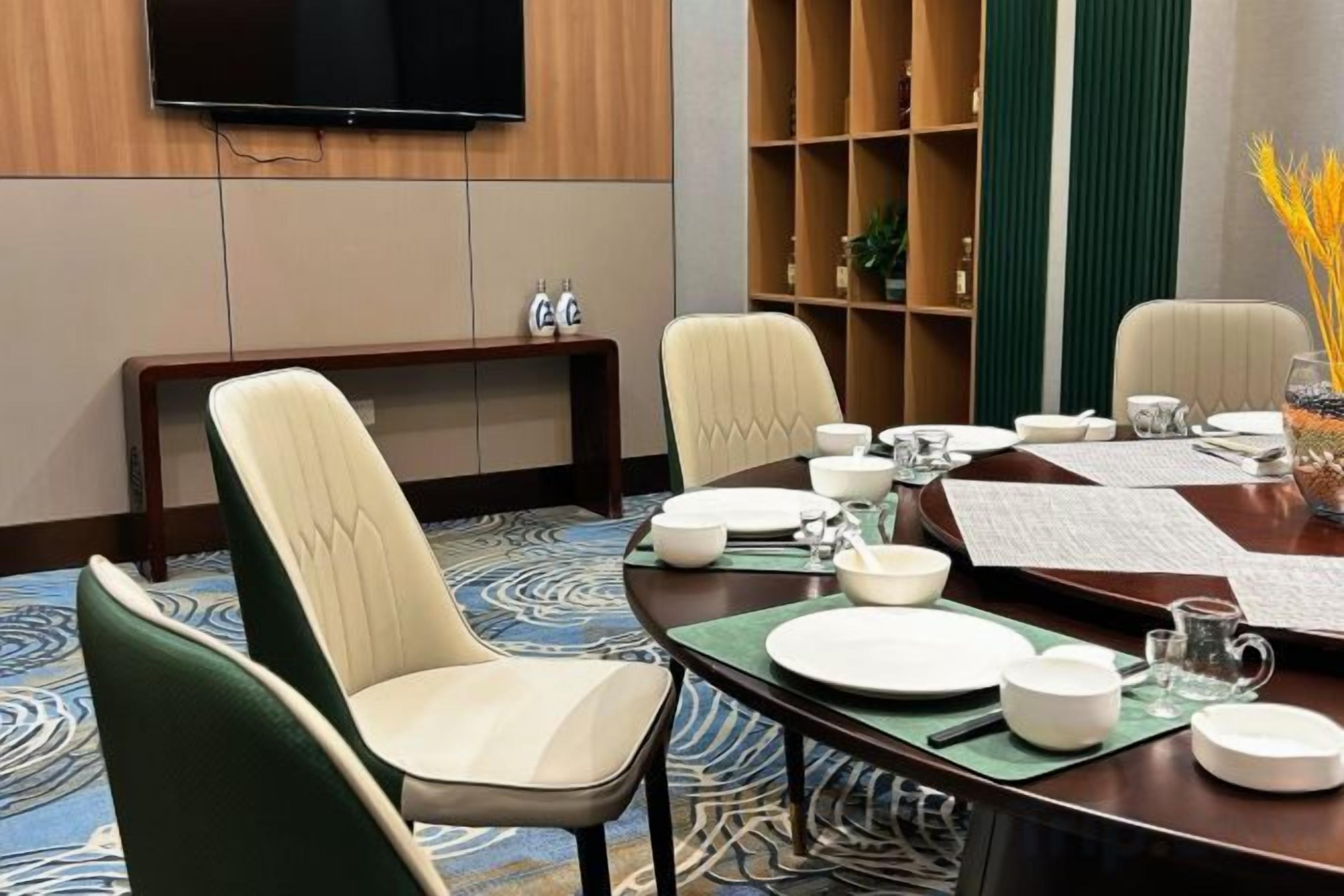 A conference room with a round table, chairs, and a television mounted on the wall.