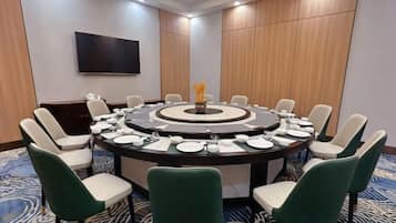 A conference room with a round table, chairs, a flat-screen TV, and a decorative centerpiece.