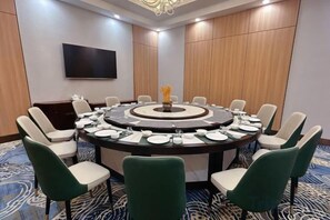 A conference room with a round table, chairs, a flat-screen TV, and a decorative centerpiece. - Inner Mongolia Hotel Duolan Hotel (Jinqiao Development Zone) (Hohhot)
