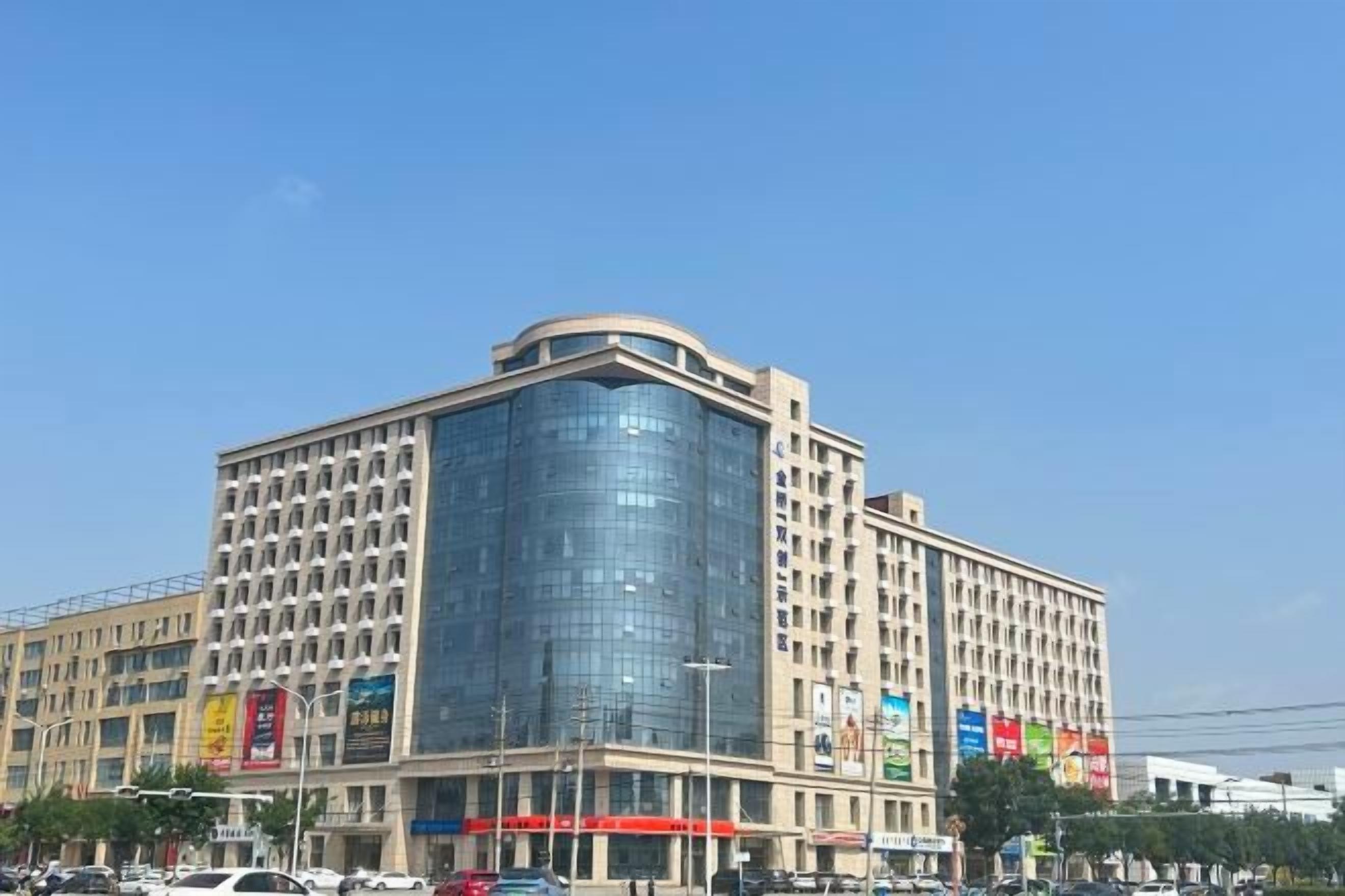 Un hôtel à plusieurs étages doté d’une façade en verre incurvée, de nombreux niveaux et d’un toit plat.
