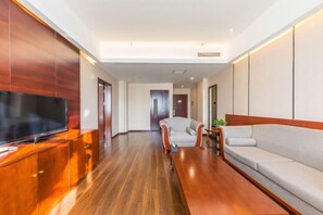 Une chambre d’hôtel moderne avec un meuble en bois, un téléviseur à écran plat, un canapé et une table à manger.