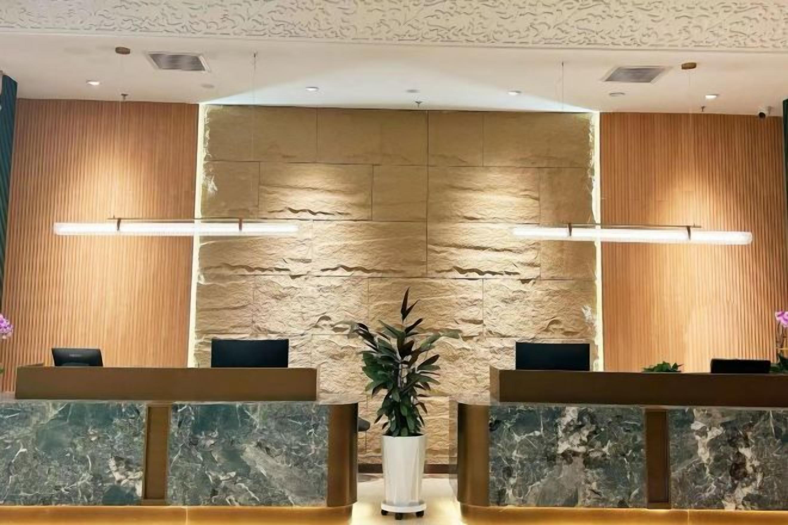 A reception area with a stone wall, marble reception desk, and a potted plant.