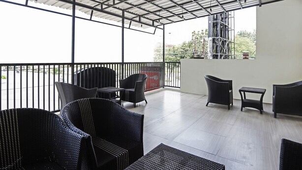 A covered outdoor seating area with wicker furniture and a view of the cityscape. - Hotel O D'lima Guest House Sub (Surabaya)
