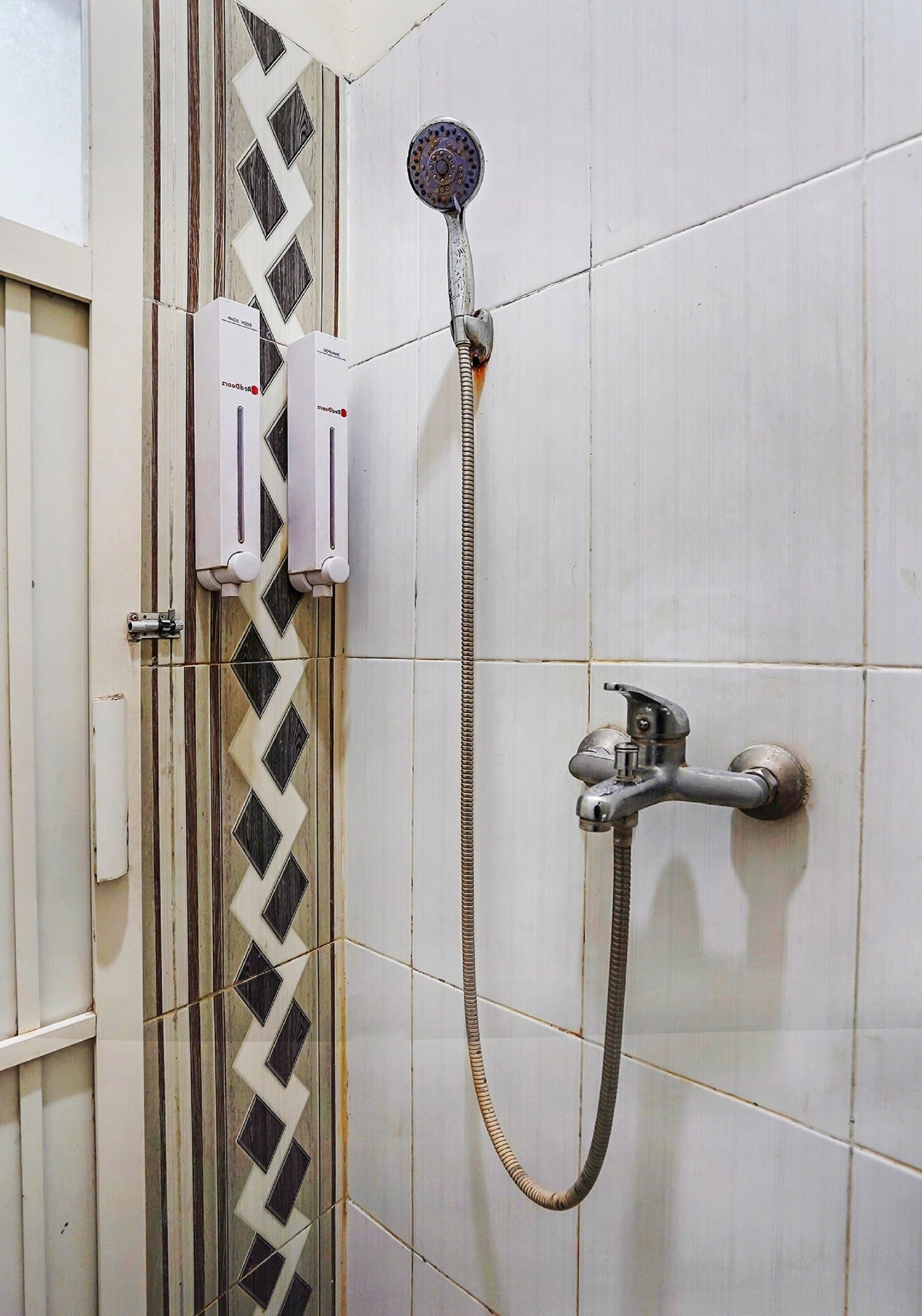 A shower with a handheld showerhead and a wall-mounted faucet.