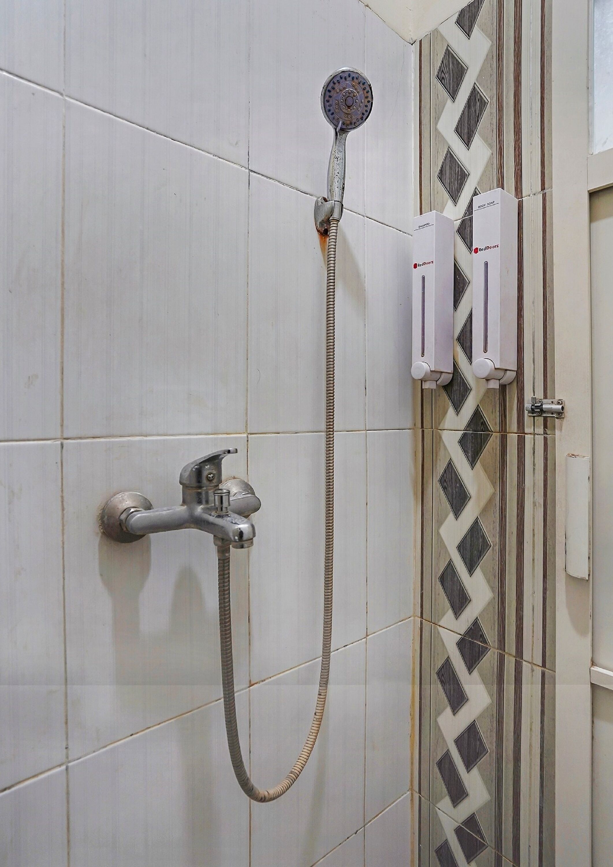 A shower with a handheld showerhead and a wall-mounted faucet.