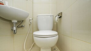 A bathroom with a white toilet, a sink, and a showerhead.