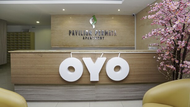 A reception desk with a sign reading "Pavilion Permata Apartment" and the name "OYO" displayed prominently.