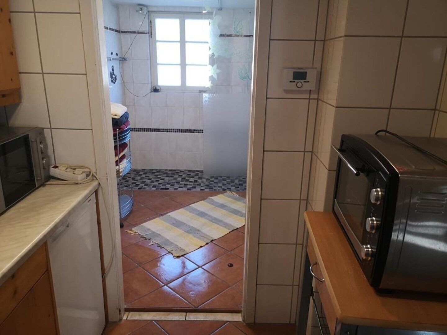 A kitchen with a microwave, toaster, and tiled walls.