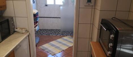 A kitchen with a microwave, toaster, and tiled walls.