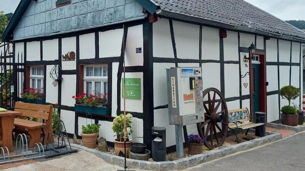 A traditional half-timbered building with a sign for 'CIGARETTES' and a vintage cart outside. - Amy's vacation home (Simmerath)