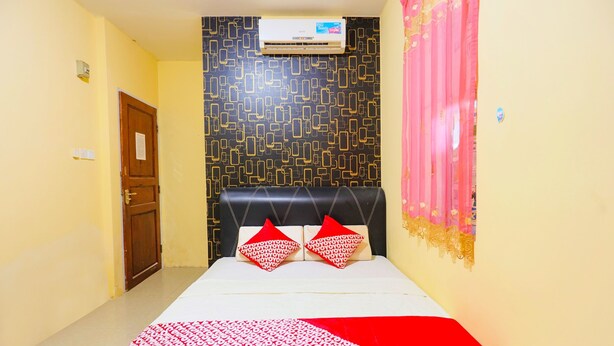 A hotel room with a bed, a patterned wall, a door, and an air conditioning unit. - OYO 91659 City Residence (Batam)