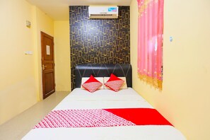 A hotel room with a bed, a patterned wall, a door, and an air conditioning unit. - OYO 91659 City Residence (Batam)
