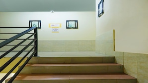 A staircase with a black handrail leading to a landing. There are two framed pictures on the wall above the landing. - OYO 91659 City Residence (Batam)