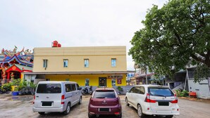 Three parked cars in front of a building with a yellow facade and a red roof. - OYO 91659 City Residence (Batam)