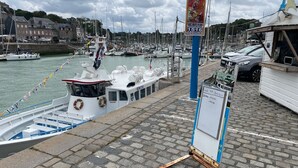 A marina with boats docked, a signboard, and a building with a blue roof. - Charming fisherman's cottage (Saint-Valery-en-Caux)