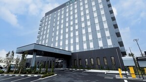 Ein modernes Hotel mit einem gut sichtbaren Schild mit der Aufschrift "HOTEL ROUTE INN", das eine saubere, rechteckige Fassade mit gleichmäßig verteilten Fenstern und einem flachen Dach aufweist.