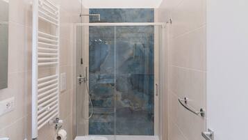 Een moderne badkamer met een douchecabine van glas, een toilet en een wastafel.