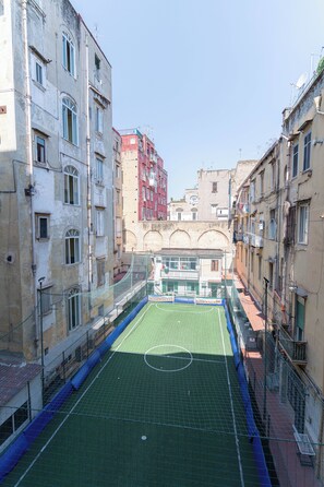A tennis court surrounded by multi-story buildings with balconies and satellite dishes. - Toto e Peppino luxury rooms (Naples)