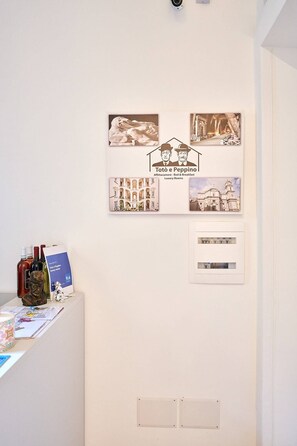 A wall with framed pictures, a sign, and a wine bottle display. - Toto e Peppino luxury rooms (Naples)