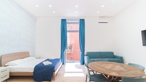 A modern hotel room with a bed, a wooden dining table, and a teal sofa. - Toto e Peppino luxury rooms (Naples)