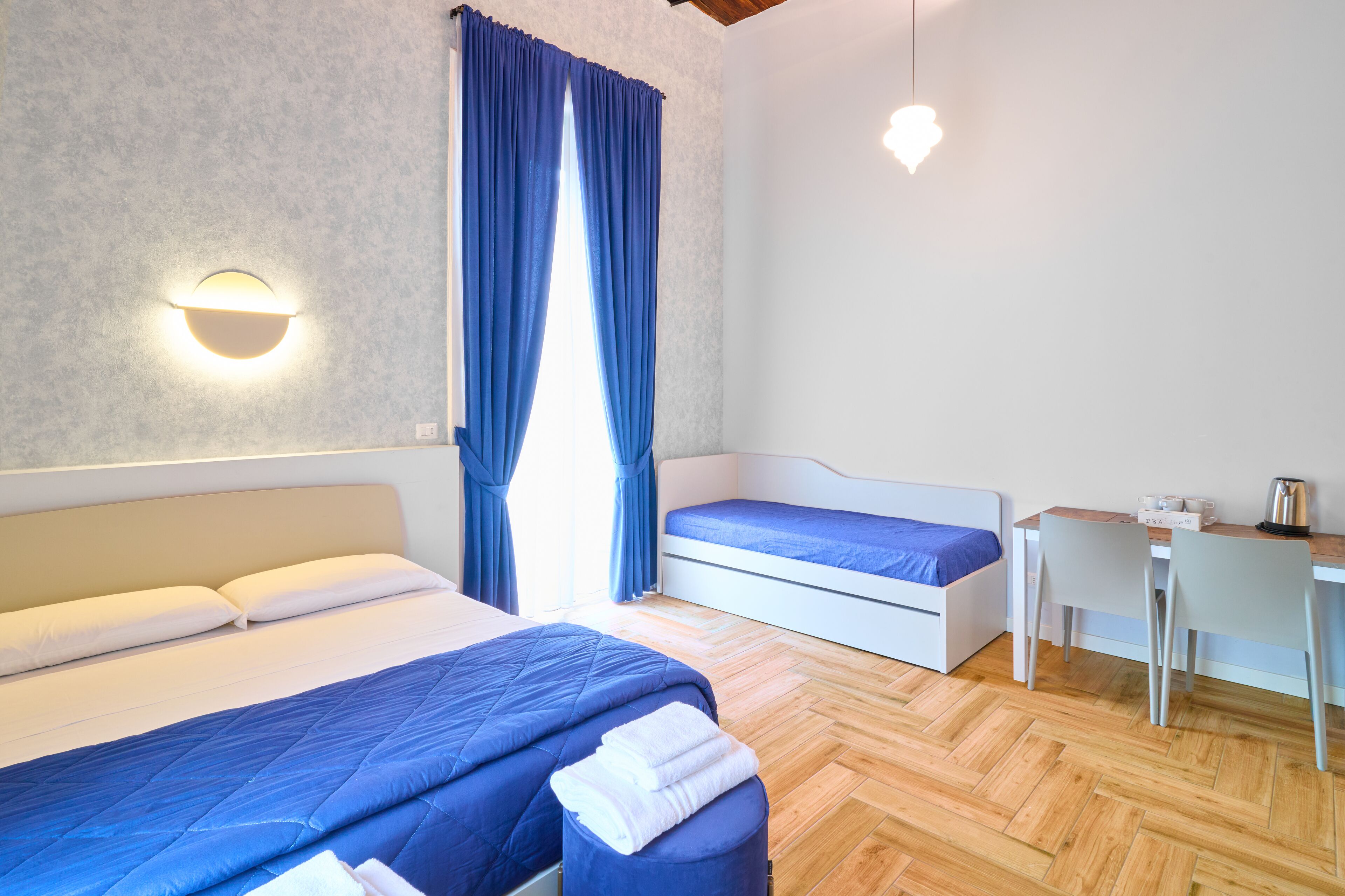 A bedroom with two beds, a desk, and a chair.