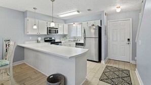 A modern kitchen with white cabinets, stainless steel appliances, and pendant lighting. - Family Beach Retreat ~ Seascape ~ 11-Pools (Panama City Beach)