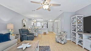 A modern living room with a ceiling fan, a sofa, a coffee table, and a TV stand. - Family Beach Retreat ~ Seascape ~ 11-Pools (Panama City Beach)