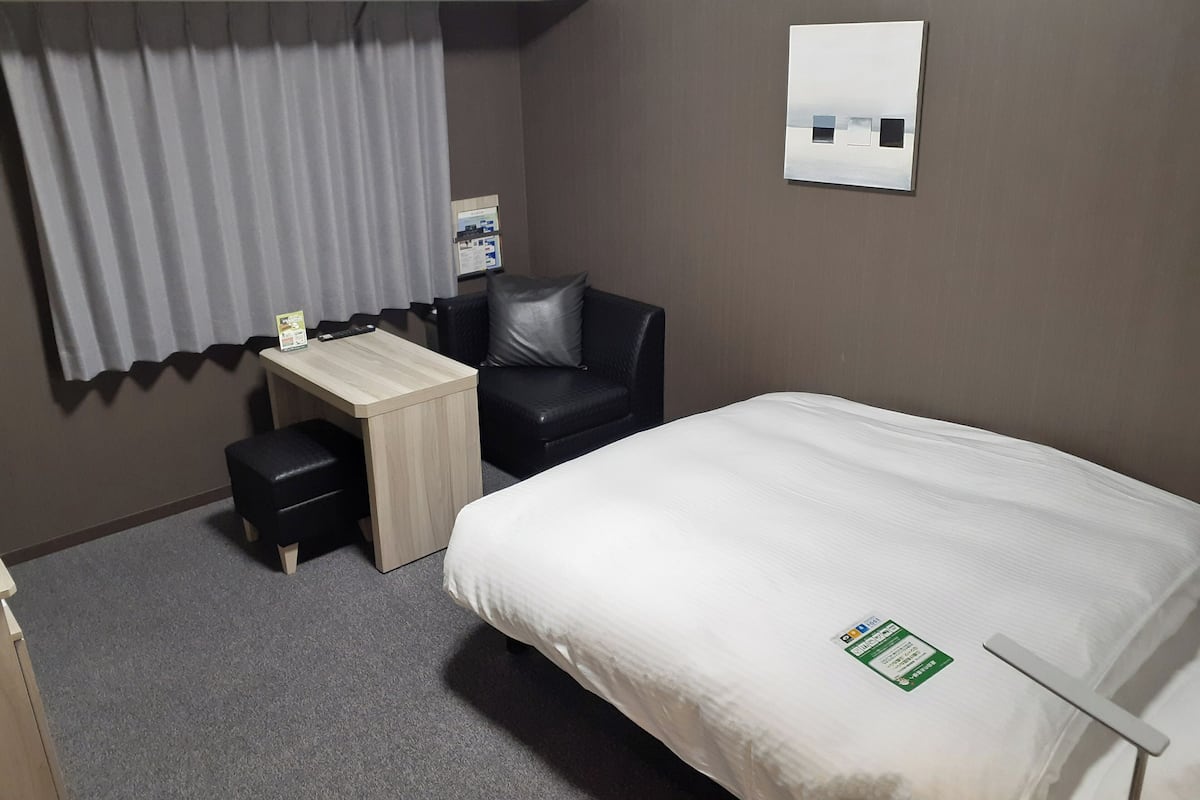 Ein Hotelzimmer mit Bett, Schreibtisch, Stuhl und kleinem Tisch.