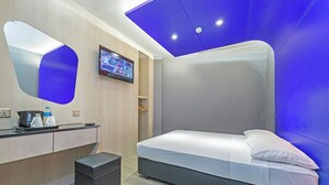 A modern hotel room with a bed, a desk with a coffee maker, a TV, and a small trash bin. - Hotel 81 Lavender (Singapore)