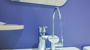 A bathroom with a chrome faucet and a white sink against a blue wall. - Hotel 81 Lavender (Singapore)
