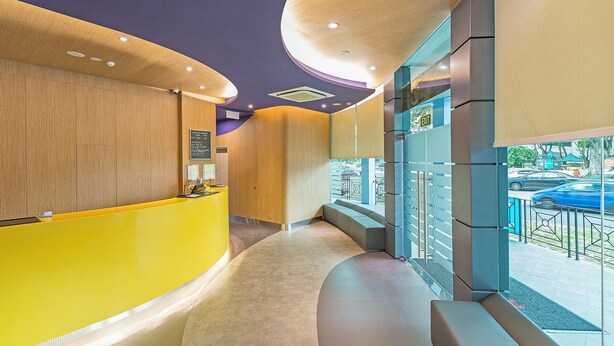 A modern hotel lobby with a curved reception desk, seating area, and a view of the street through large windows. - Hotel 81 Lavender (Singapore)