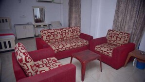 Una sala de estar con un sofá rojo y sillones, una mesita de centro de madera y un aparador blanco.