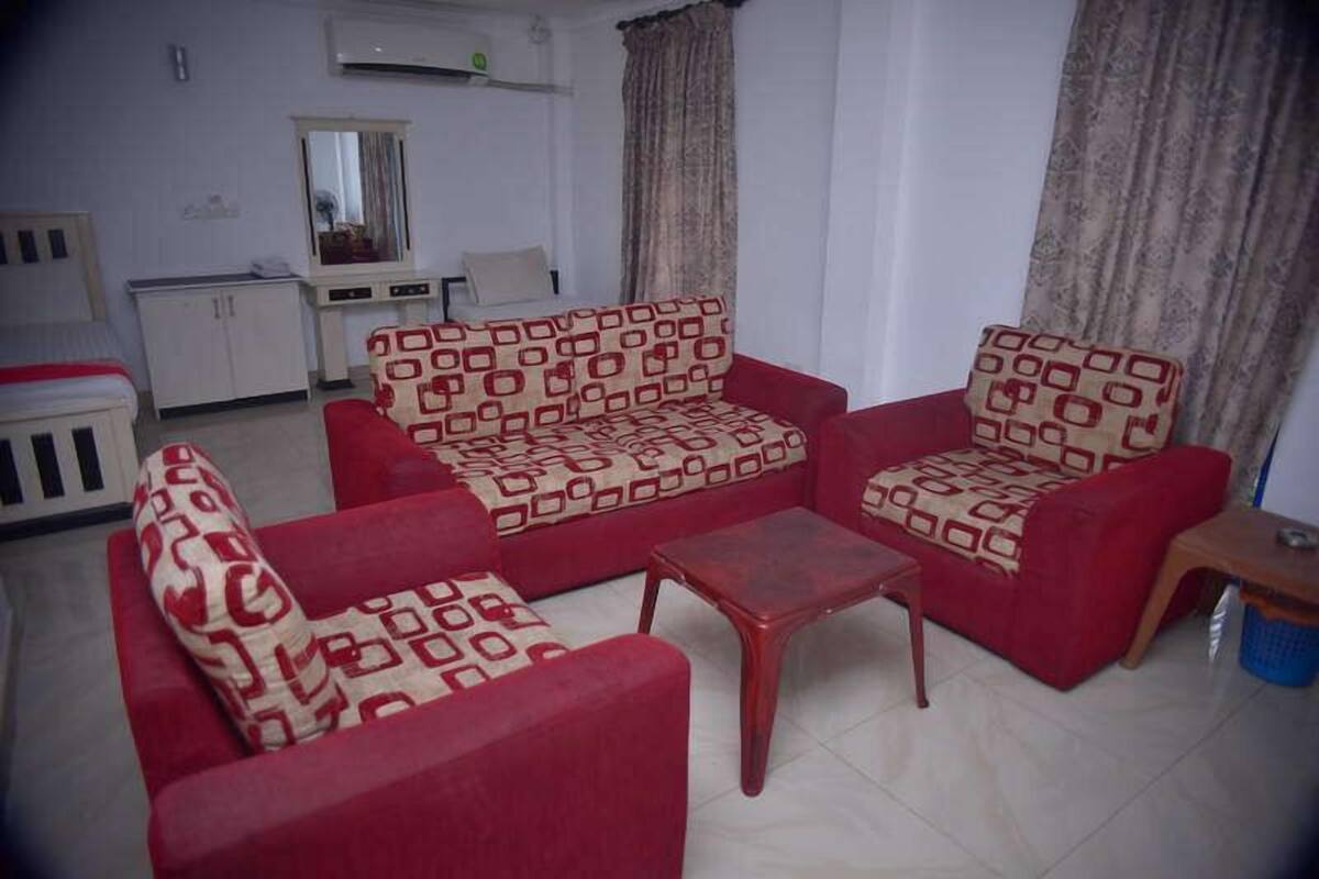Una sala de estar con un sofá rojo y sillones, una mesita de centro de madera y un aparador blanco.