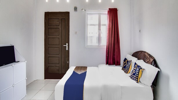 A bedroom with a bed, a wooden door, a window with curtains, and a white dresser. - Hotel O Raja Homestay Syariah (Pekanbaru)