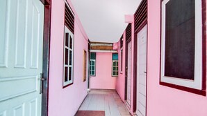 A narrow corridor with pink walls and white doors. - Hotel O Raja Homestay Syariah (Pekanbaru)