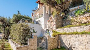 A two-story house with a stone facade, a balcony, and a gate. - Bellavista Paradise 2 (Marinella)