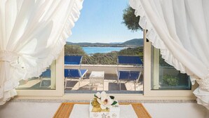 A balcony with a view of the sea, white curtains, and a small table with a floral arrangement. - Bellavista Paradise 2 (Marinella)
