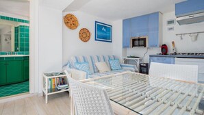 A modern kitchen with blue cabinets, a microwave, and a red kettle. - Bellavista Paradise 2 (Marinella)