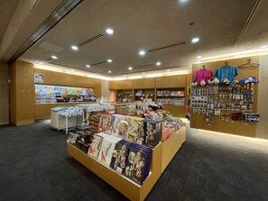 Une librairie proposant une grande variété de livres et de magazines, un rayon où sont exposés des vêtements suspendus, et un comptoir où sont présentés divers articles.