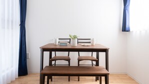 Een eetgedeelte met een houten tafel en bank, een plant in pot en twee witte pitchers.