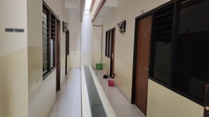 A hallway with a central drain, doors on either side, and a sign reading "HARAP TENANG". - Hotel O C16 Siwalankerto Syariah (Sidoarjo)